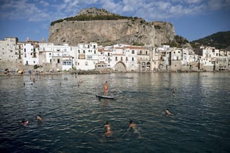 CEFALU, ITALY - JULY 10: People swim during summer season as local and foreigner tourists start to gather in Cefalu, the old town in PalermoÃ¢s province (Sicily), included in the UNESCOÃ¢s heritage list for its Arab-Norman architecture, Italy on July 10, 2022. The wide coastline, with sandy and rocky beaches, also attracts tourists. (Photo by Valeria Ferraro/Anadolu Agency via Getty Images)