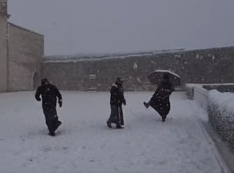 Frati francescani giovano a palle di neve fuori dalla Basilica di San Francesco