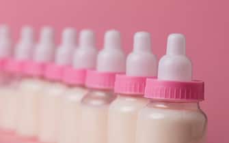 Baby bottle full of milk on a pink background
