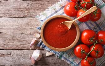 tomato sauce with garlic and basil in a wooden bowl. horizontal view from above
