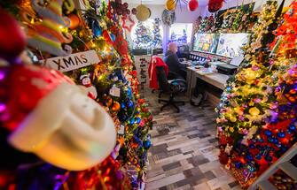 30 November 2023, Lower Saxony, Rinteln: Thomas Jeromin sits in front of his computer surrounded by Christmas trees in his home in the district of Schaumburg. 555 Christmas trees and almost 108,000 Christmas baubles: During the Advent season, the Jeromin family's house shines as a colorful Christmas world. Photo: Julian Stratenschulte/dpa (Photo by Julian Stratenschulte/picture alliance via Getty Images)