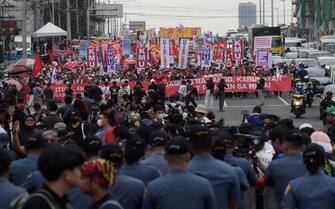 epa10765319 Filipino policemen stand guard to block marching activists during a protest rally along a road leading to the Congress compound in Quezon city, Metro Manila, Philippines, 24 July 2023. The protesters gathered against the State of the Nation Address (SONA) of President Ferdinand 'Bongbong' Marcos.  EPA/FRANCIS R. MALASIG