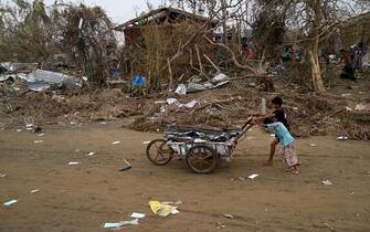 TOPSHOT - Children push a cart full of debris at the Khaung Dote Khar Rohingya refugee camp in Sittwe, in Myanmar's Rakhine state, on May 15, 2023, after cyclone Mocha made a landfall. Cyclone Mocha made landfall between Cox's Bazar in Bangladesh and Myanmar's Sittwe carrying winds of up to 195 kilometres (120 miles) per hour, the biggest storm to hit the Bay of Bengal in more than a decade. (Photo by Sai Aung MAIN / AFP) (Photo by SAI AUNG MAIN/AFP via Getty Images)