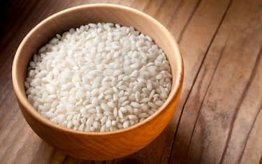 Carnaroli rice grains in wooden bowl.