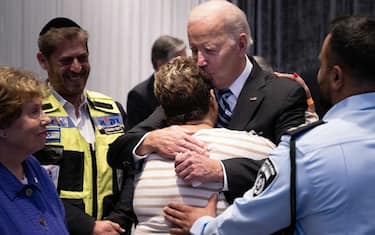 TOPSHOT - Police officer Evyatar Edri looks on, as US President Joe Biden hugs his mother Rachel Edri, who was held hostage by the Palestinian militant group Hamas, while meeting with people effected by this month's Hamas attack on Israel, on October 18, 2023, in Tel Aviv. Thousands of people, both Israeli and Palestinians have died since October 7, 2023, after Palestinian Hamas militants based in the Gaza Strip entered southern Israel in a surprise attack, holding some people hostage, that lead Israel to declare war on Hamas in Gaza on October 8. (Photo by Brendan Smialowski / AFP) (Photo by BRENDAN SMIALOWSKI/AFP via Getty Images)
