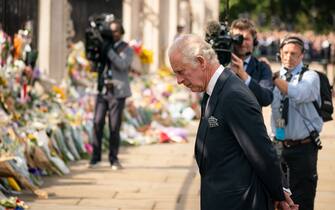 King Charles III looks at flowers outside Buckingham Palace, London after travelling from Balmoral following the death of Queen Elizabeth II on Thursday. Picture date: Friday September 9, 2022.