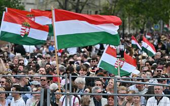 Participants display the Hungarian flag as they gather for a rally organised by Hungarian opposition figure Peter Magyar, Hungarian lawyer, former government insider and ex-husband of former Justice Minister Varga, in downtown Budapest on April 06, 2024, to denounce the Hungarian government and corruption. (Photo by Attila KISBENEDEK / AFP)