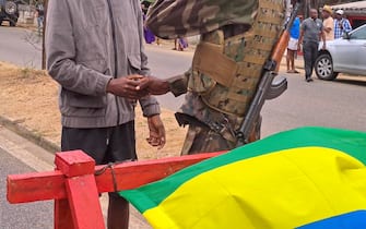 epa10828151 A man shakes hands with a Gabonese soldier in the streets of Akanda, Gabon, 30 August 2023. Members of the Gabonese army on 30 August announced on national television that they were canceling the election results and putting an end to Gabonese President Ali Bongo's regime, who had been declared the winner.  EPA/STRINGER