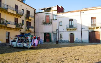 Militello in Val di Catania, Sicily: A roving vendor truck selling clothing and household supplies in a sunlit cobbled piazza in Militello, a UNESCO World Heritage site in Catania Province.