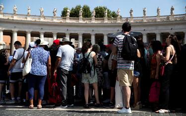 Turisti si riparano dal caldo il giorno di Ferragosto in piazza San Pietro, Roma, 15 agosto 2024. ANSA/ANGELO CARCONI