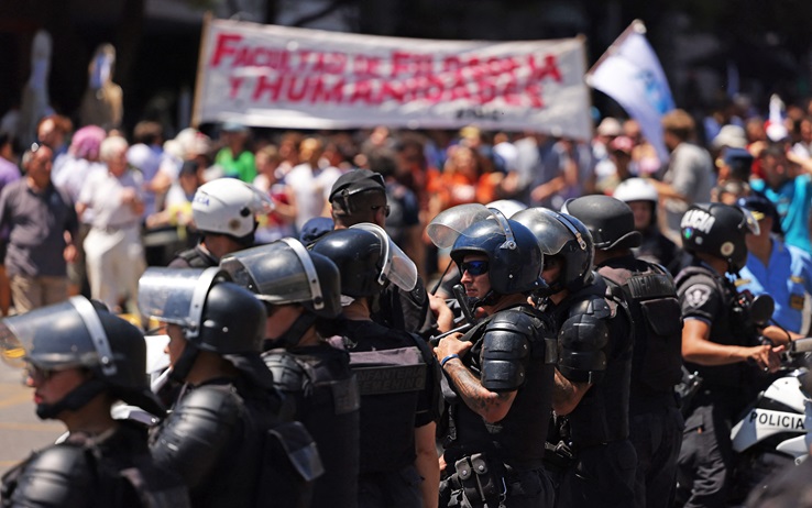 Members of the police stand guard while people take part in a demonstration during a national strike against the government of Javier Milei in Cordoba, Argentina on January 24, 2024. Argentine President Javier Milei faces the first national strike in just 45 days of government, against his draconian fiscal adjustment and his plan to reform more than a thousand laws and regulations that governed for decades. The largest Argentine union called the strike in rejection, in particular, of the changes by decree to the labor regime promoted by Milei, which limit the right to strike and affect the financing of unions. (Photo by Nicolas Aguilera / AFP) (Photo by NICOLAS AGUILERA/AFP via Getty Images)