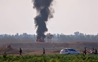 A picture taken from Khan Yunis in the southern Gaza Strip shows smoke billowing next to an Israeli observation tower on October 7, 2023. Barrages of rockets were fired at Israel from the Gaza Strip at dawn as militants from the blockaded Palestinian enclave infiltrated Israel, with at least one person killed, the army and medics said. (Photo by SAID KHATIB / AFP) (Photo by SAID KHATIB/AFP via Getty Images)