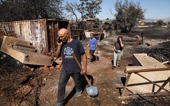 epa11547402 People walk in a burnt farmland after a wildfire in the area of Chalandri, close to Athens city, Greece, 13 August 2024. A wildfire that broke out on 11 August in the outskirts of Athens and spread to a large part of northeastern Attica no longer had a single front on 13 August. The fire stretched along a front more than 30 kilometres in length. According to the Fire Brigade, the firefighting forces are dealing with scattered pockets of fire from Varnavas to Nea Makri and Penteli while there are constant rekindlings. Firefighters found a charred body, of a 60-year-old woman, in a small factory that caught fire in Patima Halandriou.  EPA/GEORGE VITSARAS