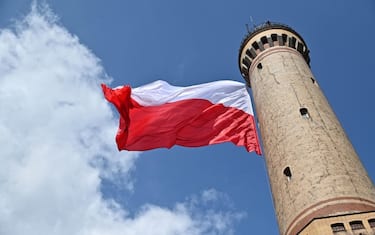 epa09922437 A giant Polish national flag flies at a lighthouse as part of celebrations on the occasion of the Polish National Flag Day, in Swinoujscie, northwestern Poland, 02 May 2022. The flag measures 500 square meters and was hung at a height of almost 60 meters. The Polish National Flag Day is celebrated annually on 02 May.  EPA/Marcin Bielecki POLAND OUT