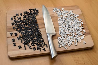 Wooden plate with small alphabet-letters and a big knife.