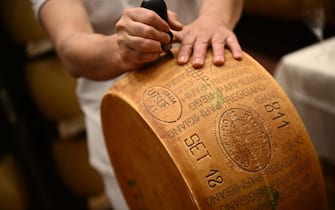 A worker cuts a wheel of Parmigiano Reggiano cheese at the Casearia Castelli, member of Lactalis Group, at the Caseificio Tricolore in Reggio Emilia, Northern Italy, on April 19, 2023. - The global dairy giant Lactalis, which has remained a family business since it was founded in 1933 in Laval, France, announced on April 20, 2023 that it would have sales of more than 28 billion euros by 2022, dethroning Danone as the leading French food company, and joining the world's top 10 in the food industry. (Photo by Marco BERTORELLO / AFP) (Photo by MARCO BERTORELLO/AFP via Getty Images)