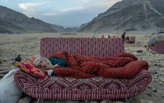 An Afghan refugee rests in the desert next to a camp near the Torkham Pakistan-Afghanistan border, in Torkham, Afghanistan, Friday, Nov. 17, 2023. A huge number of Afghans refugees entered the Torkham border to return home hours before the expiration of a Pakistani government deadline for those who are in the country illegally to leave or face deportation. (AP Photo/Ebrahim Noroozi)