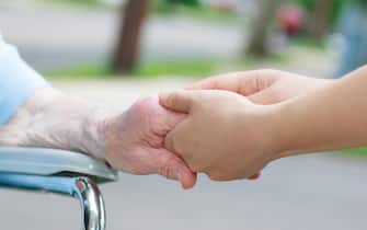 Caregiver holding an elderly womans hand outside