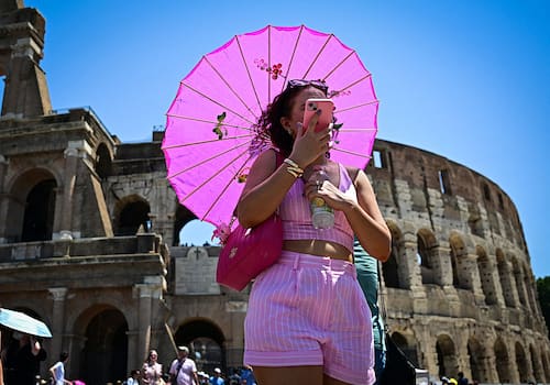 A woman holds an umbrella to protect herself from the sun on a hot summer day near the Colosseum in Rome on July 01, 2025. (Photo by Tiziana FABI / AFP) (Photo by TIZIANA FABI/AFP via Getty Images)          