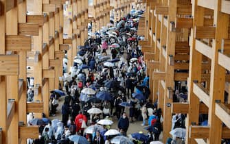 epa12028555 Visitors gather under the Grand Ring as rain is falling after the opening of the Osaka Expo 2025 in Osaka, western Japan, 13 April 2025. The Expo 2025 Osaka, Kansai, Japan will be open to the public until 13 October 2025.  EPA/FRANCK ROBICHON