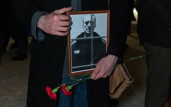 ST  PETERSBURG, RUSSIA - 2024/02/16: A man holds flowers and a portrait of the Russian opposition leader Alexei Navalny at the monument of victims of political repression in St. Petersburg. (Photo by Andrei Bok/SOPA Images/LightRocket via Getty Images)