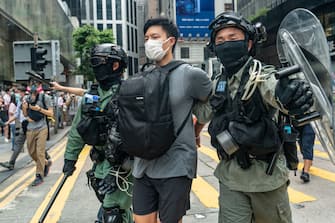 HONG KONG, CHINA - MAY 27: A pedestrian is detained by riot police during a Lunch with You rally in Central district on May 27, 2020 in Hong Kong, China. Chinese Premier Li Keqiang said on Friday during the National People's Congress that Beijing would establish a sound legal system and enforcement mechanism for safeguarding national security in Hong Kong.(Photo by Anthony Kwan/Getty Images)