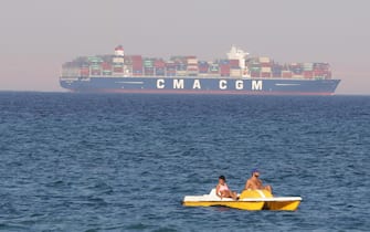 epa06958961 Egyptians enjoy the sea on a pedal boat as a cargo ship crosses the Gulf of Suez towards the Red Sea at El Sokhna beach in Suez, Egypt, 130 km east of Cairo, Egypt, 19 August 2018  EPA/KHALED ELFIQI