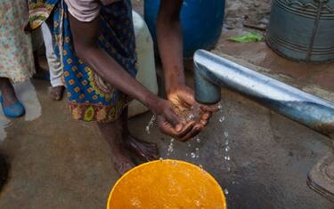 A young local girl, dressed in traditional clothing, washes her hands and drinks water from a borehole, in Nsanje District, southern Malawi. On the countryside of Malawi, people often have to walk long distances to get water from the nearest pump.