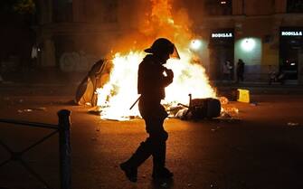 A member of the police forces walks past trash bins burning on the street during a protest called by far-right and right-wing movements against government negotiations for granting an amnesty to people involved with Catalonia's failed 2017 independence bid, near to the Spanish Socialist Party (PSOE) headquarters in Madrid, on November 9, 2023. For the las few days thousands of right-wingers and far-right demonstrators have gathered outside the Socialist Party headquarters in Madrid in tense protests against the government's proposed law granting amnesty to Catalan separatists. Spanish Prime Minister Pedro Sanchez has clinched a controversial deal to remain in power by offering amnesty to Catalan separatists, raising tensions across the country. The accord is aimed at "giving stability to the four-year legislature," Spanish Socialist Party (PSOE) official Santos Cerdan told a news conference in Brussels today after negotiations with Catalan separatist leader Carles Puigdemont, who is based there. (Photo by Pierre-Philippe MARCOU / AFP) (Photo by PIERRE-PHILIPPE MARCOU/AFP via Getty Images)