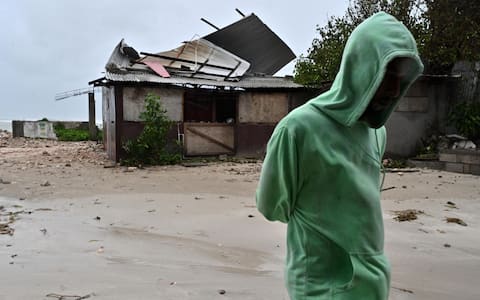 epaselect epa12486754 A man walks by a house damaged by the preliminary winds of Hurricane Melissa at Hellshire Fishing Beach in Portmore, Jamaica, 27 October 2025. Jamaican Prime Minister Andrew Holness said the government has a multifaceted plan to ensure a 'swift and effective' response to the storm