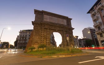 Milan, Italy - August 6, 2020: twilight long exposure of a street view in Porta Romana, a landmark with an ancient roman arch. Background is a dusk sk