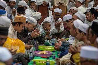 Muslims are praying during a mass break-fasting on the 27th night of Ramadan in Kampung Arab, West Jakarta, Indonesia, on April 6, 2024. Since the 18th century, the local residents of Kampung Arab in Pekojan, West Jakarta, have been holding an annual iftar gathering on every 27th of Ramadan. Participants are not only locals but also come from other cities in West Java and Central Java. The highly-anticipated event is visible on the streets around the hosting mosque. During the tradition, popular Middle Eastern dishes such as kebuli rice are being prepared. Uniquely, the tradition is held for men, while women are only allowed to hold the gathering at their homes. The tradition also allows them to meet with relatives and family members they haven't seen in a long time. (Photo by Afriadi Hikmal/NurPhoto via Getty Images)
