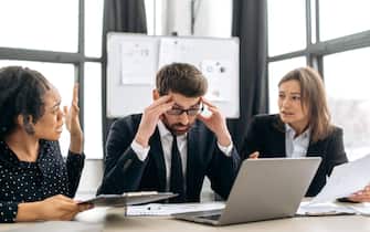 Quarrel in the work team. Irritated business employees of different nationalities, work at the workplace in modern office, argue over work issues, cannot agree, experience stress from working together
