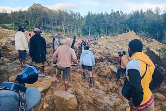 People gather at the site of a landslide in Maip Mulitaka in Papua New Guinea's Enga Province on May 24, 2024. Local officials and aid groups said a massive landslide struck a village in Papua New Guinea's highlands on May 24, with many feared dead. (Photo by AFP) (Photo by STR/AFP via Getty Images)