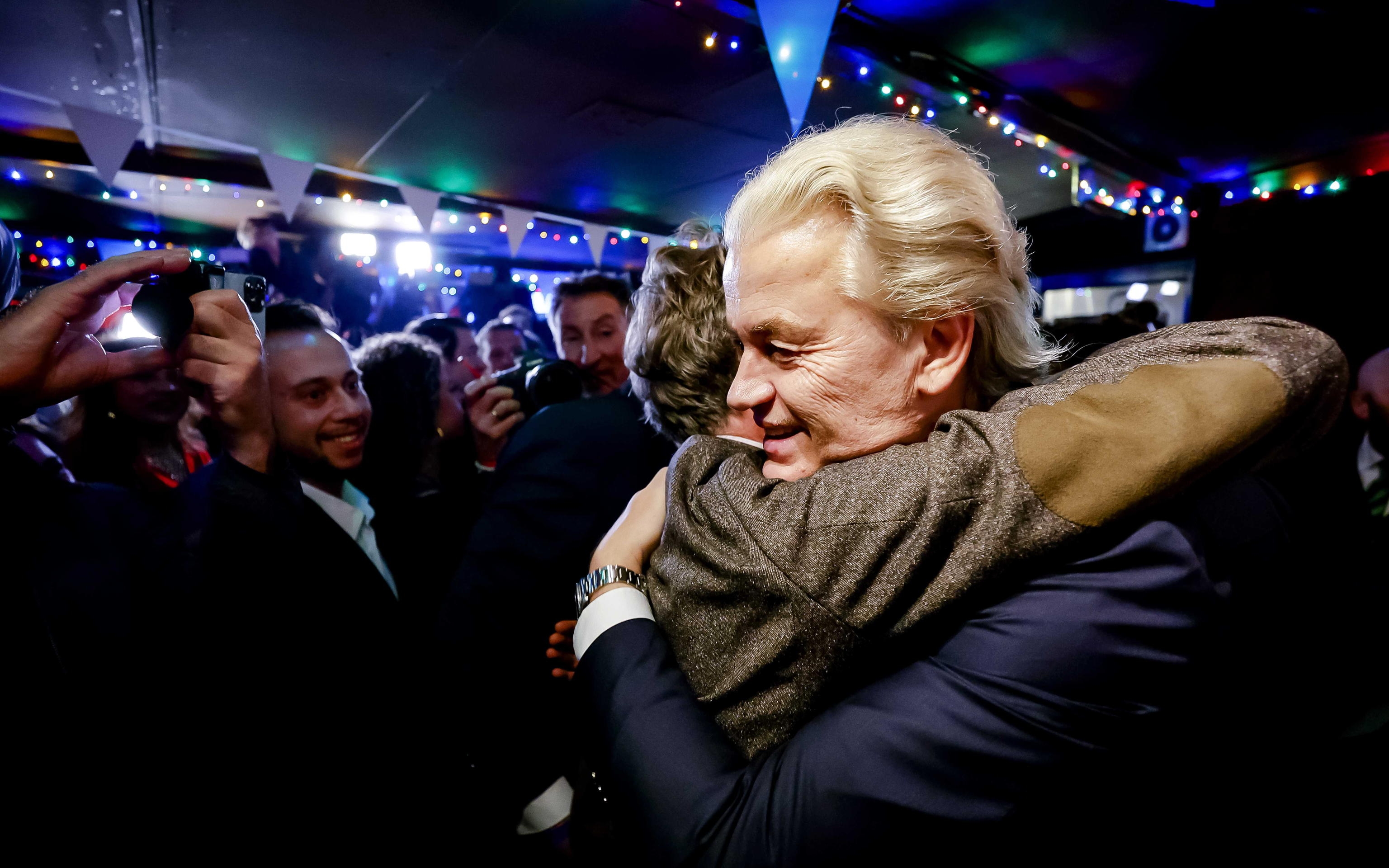 epa10990069 PVV leader Geert Wilders (R) is hugged as he responds to the results of the House of Representatives elections in Scheveningen, Netherlands, 22 November 2023. Dutch voters headed to the polls on 22 November to elect the members of the House of Representatives and a new prime minister, after Netherlands' longest-serving prime minister, Mark Rutte's cabinet collapsed in July.  EPA/REMKO DE WAAL