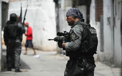Militariy police officers patrol during the Operacao Contencao (Operation Containment) at the Vila Cruzeiro favela, in the Penha complex, in Rio de Janeiro, Brazil, on October 28, 2025. At least 2,500 security forces agents took part in an operation to arrest drug traffickers from the Comando Vermelho (CV), which resulted in 18 suspects and several police officers dead. (Photo by Mauro PIMENTEL / AFP)
