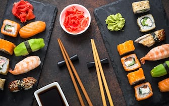Sushi, maki, nigiri and sushi roll set on dark stone table top view. Japanese food.