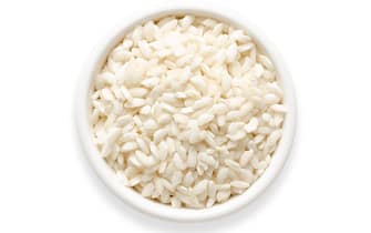 Carnaroli rice in a white bowl on white background. Square format. Top view.