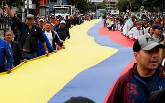 epa11312831 People carry a large Colombian flag during a march marking International Workers' Day in Bogota, Colombia, 01 May 2024. Social and union organizations commemorate International Workers' Day with demonstrations to demand labor and salary improvements for workers.  EPA/Carlos Ortega