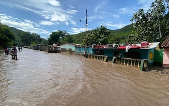 TOPSHOT - People stand outside their flooded homes after a river swelled due to heavy rains following the passage of Hurricane Beryl on the road from Cumana to Cumanacoa, Sucre State, Venezuela, on July 2, 2024. Hurricane Beryl churned towards Jamaica Tuesday after killing at least five people and causing widespread destruction across the southeastern Caribbean, threatening deadly winds and storm surge as it approached. (Photo by Victor GONZALEZ / AFP) (Photo by VICTOR GONZALEZ/AFP via Getty Images)
