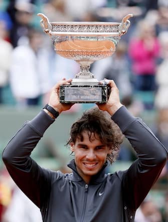 epa03259459 Rafael Nadal of Spain celebrates with the trophy after winning his final match against Novak Djokovic of Serbia for the French Open tennis tournament at Roland Garros in Paris, France, 11 June 2012.  EPA/IAN LANGSDON