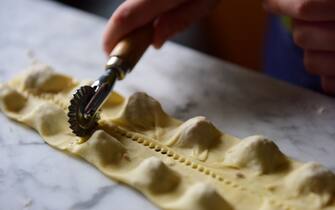 Separating pasta parcels using a pasta cutter wheel to make tortellini. One of the steps in the preparation of homemade tortellini, pasta parcels stuffed with beef, egg, parmesan cheese, in a kitchen in Italy