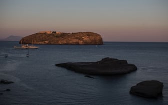 VENTOTENE, ITALY - JULY 14: Santo Stefano Island with its bourbon prison and Cala Nave beach at Sunset, on July 14 2020 in Ventotene, Italy. The prison camp was created under the Bourbons and restructured under Benito Mussolini on the nearby island of Santo Stefano. There, up to 700 opponents, including 400 communists, were incarcerated between 1939 and 1943. One of them was Altiero Spinelli who wrote there a text now known as the Ventotene Manifesto, promoting the idea of a federal Europe after the war. Prisoners also included former Italian President, the late Sandro Pertini. The tiny Island of Ventotene is one of the Pontine Islands in the Tyrrhenian Sea together with Santo Stefano, Ponza, Palmarola and Zannone, all located in the Tyrrhenian Sea. The island, the remains of an ancient volcano, is elongated, with a length of 3 kilometres (2 miles) and a maximum width of about 800 metres (2,625 feet).Since 1997 the marine area surrounding both Ventotene and Santo Stefano island is a protected area. Ventotene together with the Pontine Island of Ponza stayed free from COVID19 as no cases were registered since the Pandemic spread through out Italy in February 2020. (Photo by Alessandra Benedetti - Corbis/Corbis via Getty Images)