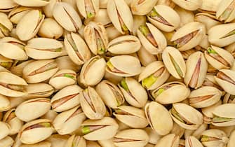 Roasted and salted pistachio seeds with shell, background, from above. Snack food, made from fruits of Pistacia vera.