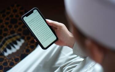 Asian muslim men Reading Quran on Smartphone Apps over the soulder