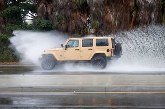 epa10811133 A car drives through standing water on a road in Long Beach, California, USA, 20 August 2023. Southern California is under a tropical storm warning for the first time in history as Hilary makes landfall. The last time a tropical storm made landfall in Southern California was 15 September 1939, according to the National Weather Service.  EPA/CAROLINE BREHMAN