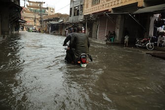 RAWALPINDI, PAKISTAN - AUGUST 14: People try to pass a flooded street with a motorcycle after a heavy rain on the eve of Pakistan's Independence Day in Rawalpindi, Pakistan on August 14, 2023. Heavy rains caused flood in low-lying areas in the city that damage to property. (Photo by Muhammad Reza/Anadolu Agency via Getty Images)