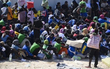 LAMPEDUSA ISLAND, ITALY - SEPTEMBER 14: A view of crowd outside of the hotspot as nearly 7,000 irregular migrants arrive in Lampedusa island of Italy on September 14, 2023. Located on the Mediterranean route leading from Africa to Europe, Lampedusa welcomed 5,112 irregular migrants on Tuesday, and the flow continued even at night with over a thousand more, according to state-run news agency ANSA. After a group of Lampedusans protested against the arrival of the migrants with a sit-in outside the town hall later in the day, the Lampedusa City Council held an emergency meeting and declared a state of emergency on the island. People working in the humanitarian assistance are facing increasing difficulties in transferring and hosting people in the hotspot, which could normally host 400 migrants. Local and regional authorities asked help from the Italian Government to deal with the emergency situation. (Photo by Valeria Ferraro/Anadolu Agency via Getty Images)