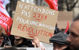 A protester holds a placard which reads "Let's not wait until 2789 for a new revolution" during in the 11th day of action after the government pushed a pensions reform through parliament without a vote, using the article 49.3 of the constitution, in Strasbourg, eastern France, on April 6, 2023. - France on April 6, 2023 braced for another day of protests and strikes to denounce French President's pension reform one day after talks between the government and unions ended in deadlock. (Photo by PATRICK HERTZOG / AFP)