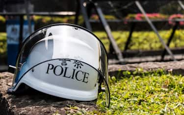 Police helmet sitting on the ground in front of police barricades.